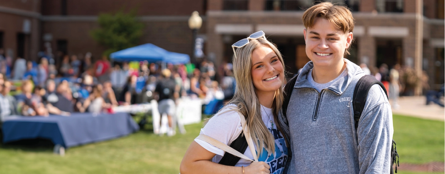 Two students smiling together outdoors during fair.