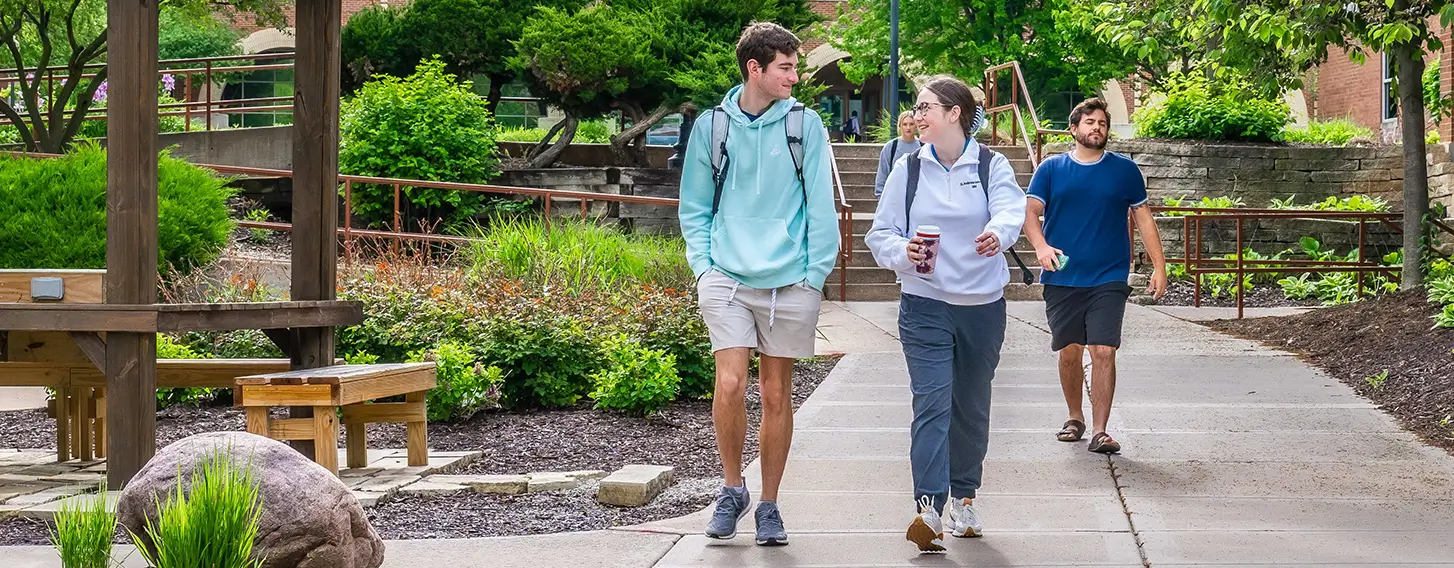 Four students walking outside away from the library