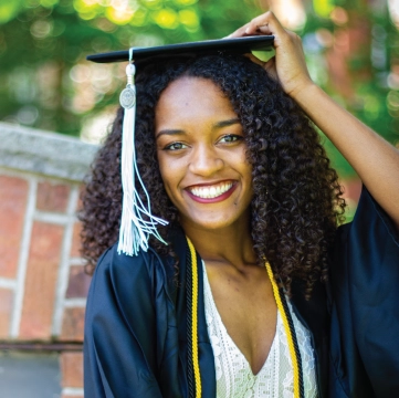 Photo of Faith Boyd smiling outdoors wearing cap and gown.