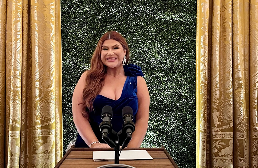 Briana Morales en vestido negro, frente a un muro verde.