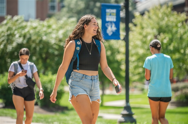 young woman walking across campus on the first day of classes