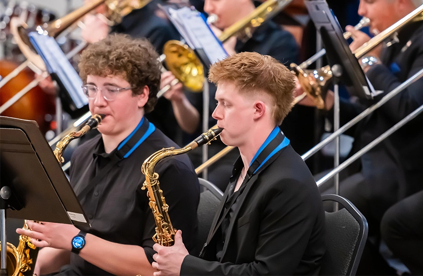 Two students play the saxophone during a concert.