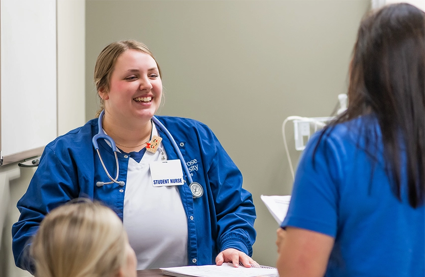Student nurses smile at each other during a clinical at St. Ambrose University.