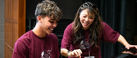 A St. Ambrose University instructor guides a student in playing the piano during the St. Ambrose University Piano camp.