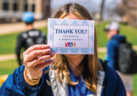 Student holds up postcard that reads 