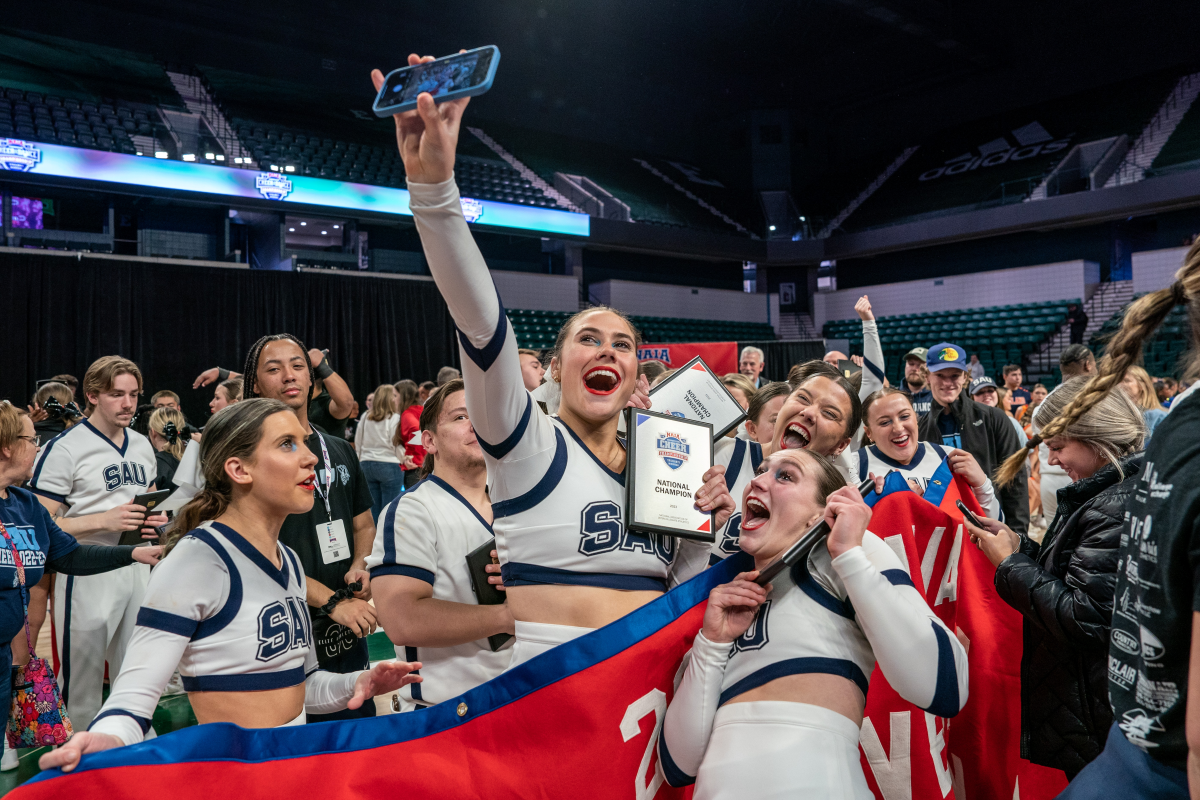 Cheerleaders celebrate with national championship trophy.