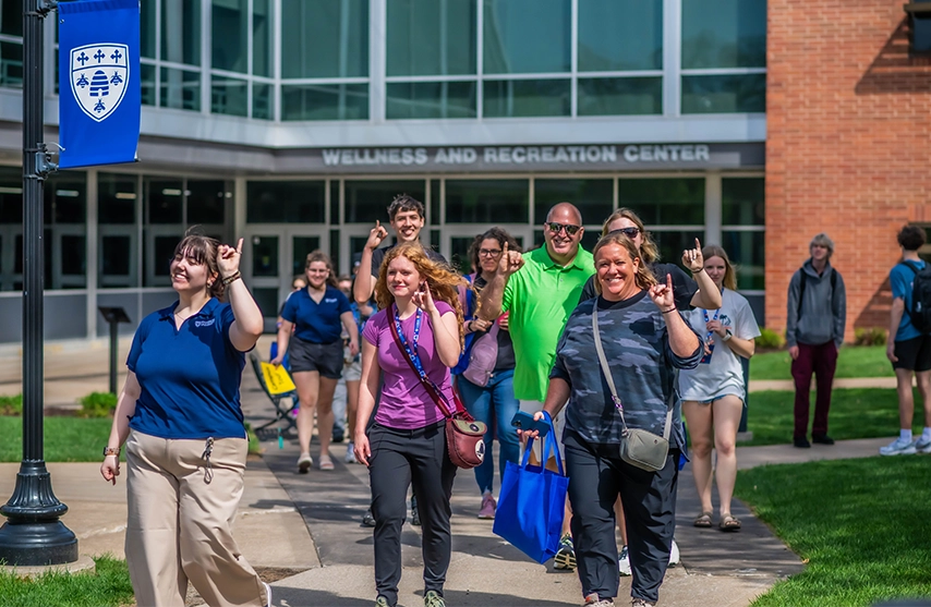 A student tour guide leads a group of students and families past the Wellness and Recreation Center at St. Ambrose University.