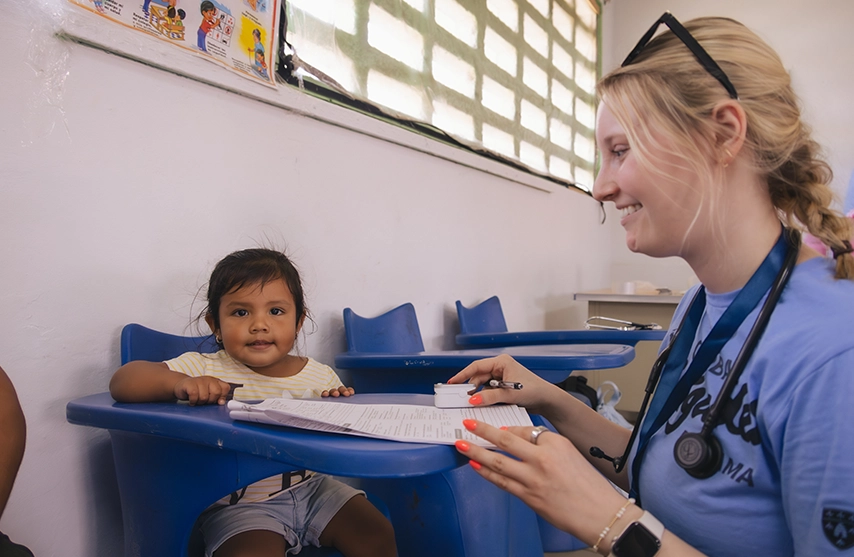 A St. Ambrose University student works with a small baby during a global brigades trip.