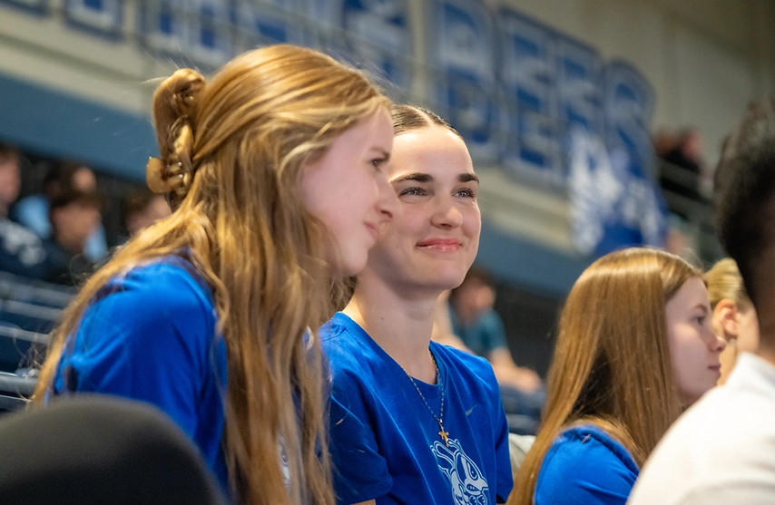 Students sit together and smile at St. Ambrose University.