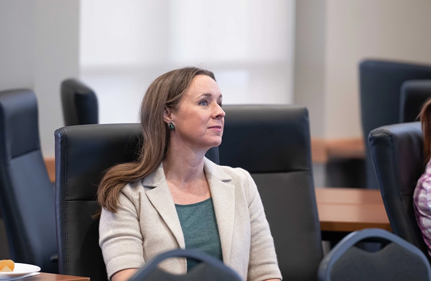 A woman in a blazer looks off to the right.