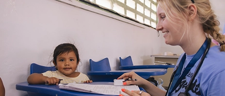 A St. Ambrose University student works with a small baby during a global brigades trip.