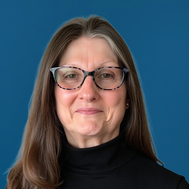 Donna Liljegren smiles into the camera against a blue background.